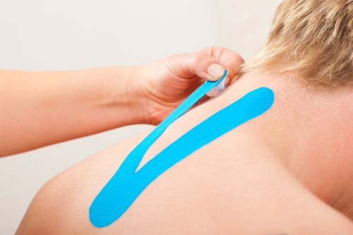 Fisioterapeuta aplicando un vendaje neouromuscular en la espalda de un paciente