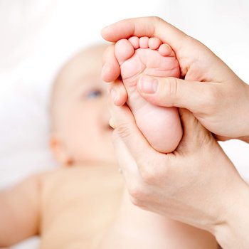 Fisioterapeuta aplicando un masaje terapéutico a un bebé en el pie