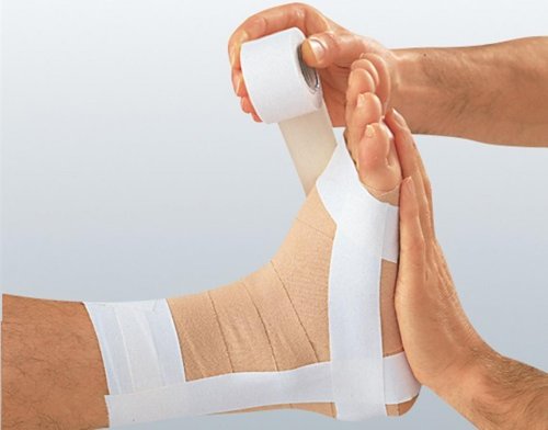 Fisioterapeuta aplicando un vendaje funcional en el pie del paciente